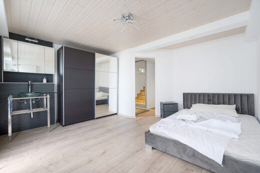 room / bedroom featuring light wood-style floors, a wood ceiling with exposed beams, and connected bathroom