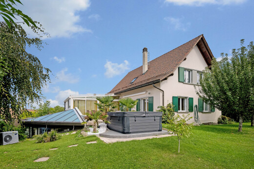 outdoor house featuring a hot tub, a yard, stucco siding, and a chimney
