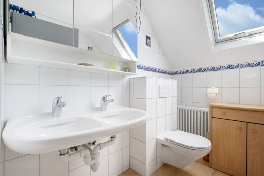 bathroom with radiator heating unit, tile walls, vaulted ceiling, a skylight, and light tile patterned floors