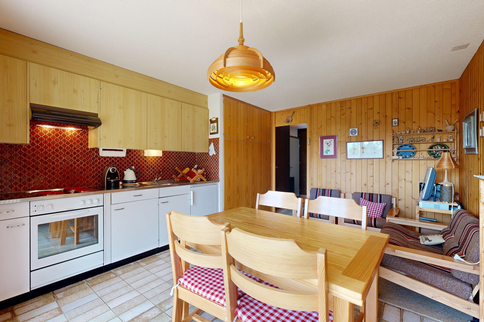 kitchen with white oven, range hood, hanging light fixtures, and wood walls
