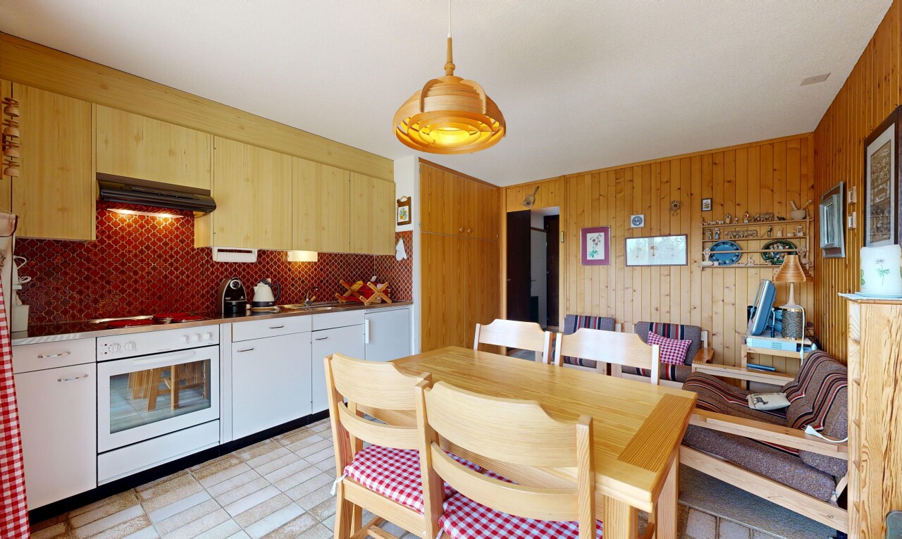 kitchen with white oven, range hood, hanging light fixtures, and wood walls