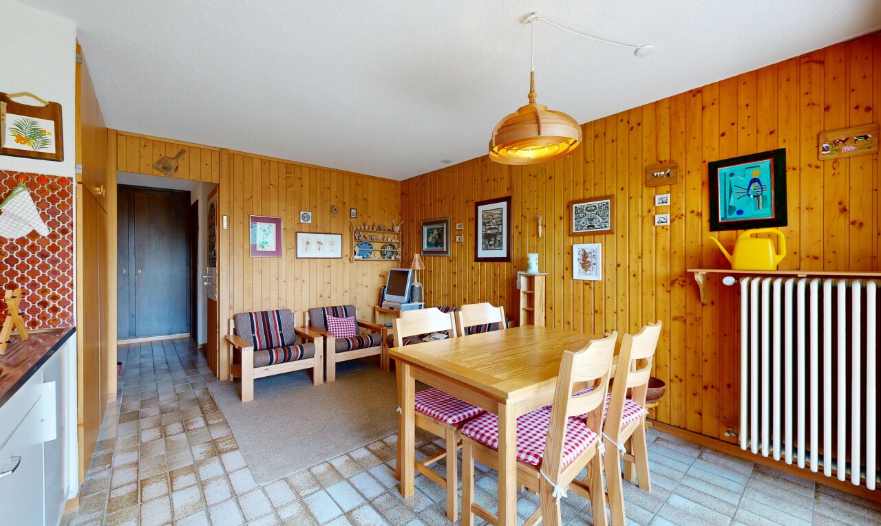 dining space featuring light floors, radiator heating unit, and wood walls