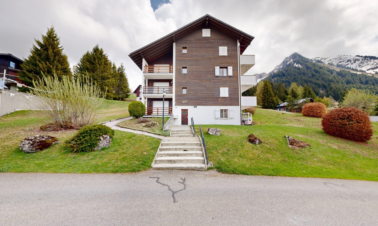 view of home featuring a balcony, a lawn, and a mountain view