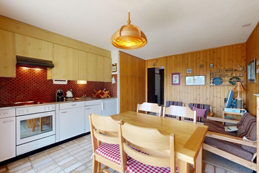 kitchen with white oven, range hood, hanging light fixtures, and wood walls