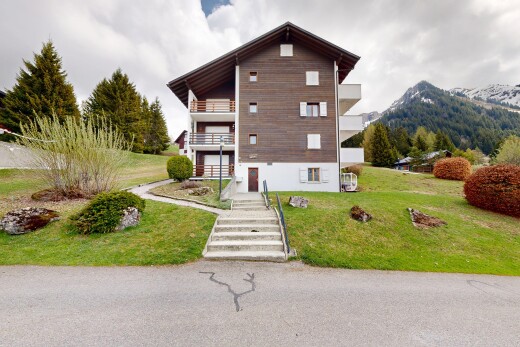 view of home featuring a balcony, a lawn, and a mountain view