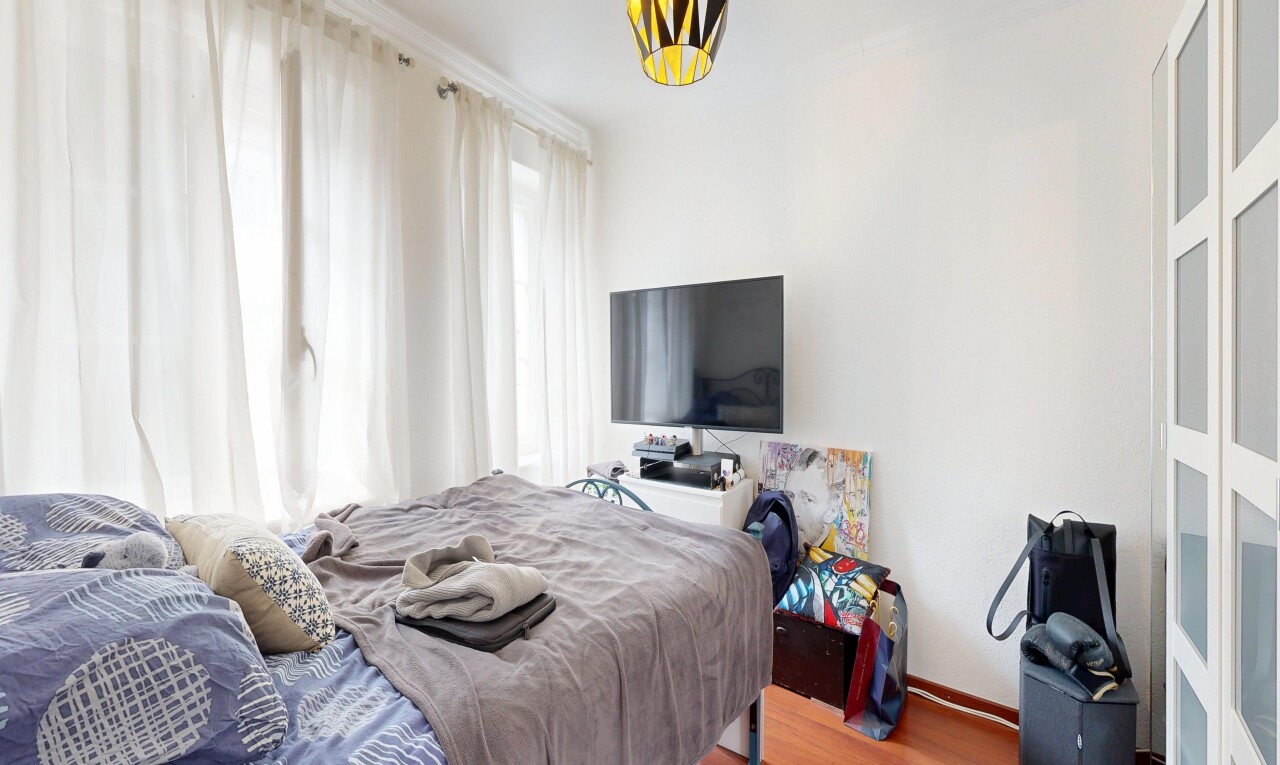 chambre avec télévision, cloison sèche, drywall, sol en finition bois, et wood finish floor