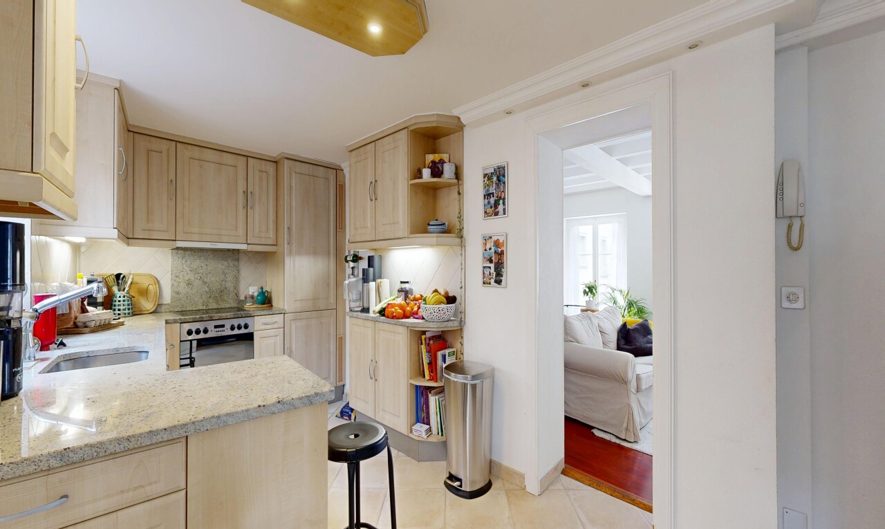 cuisine avec armoires marron clair, light brown cabinets, plans de travail en pierre, stone countertops, et light countertops