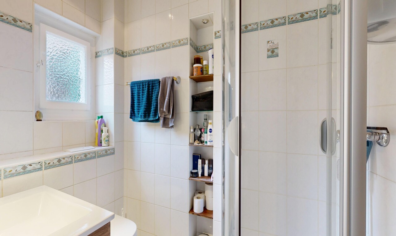 salle de bains avec lavabo (ou coiffeuse selon le contexte), tile wall, mur en carrelage, douche, et salle de bain complète