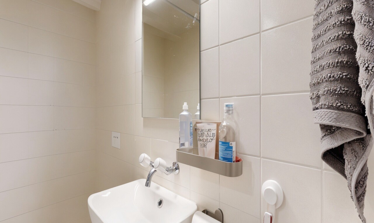 salle de bains avec mur en carrelage, tile wall, miroir, évier, et toilette