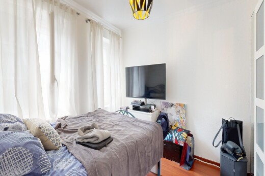 zimmer / schlafzimmer mit fernseher, gipskartonwand, drywall, holzfußboden, und wood finish floor