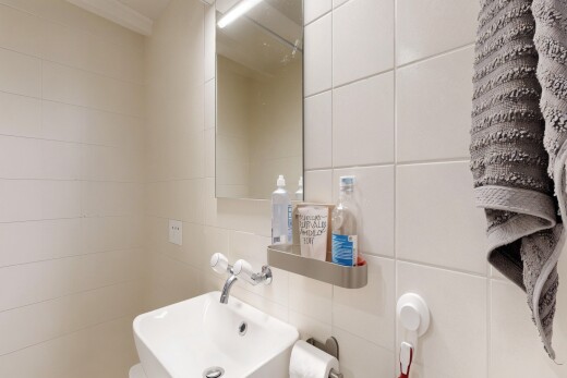 salle de bains avec mur en carrelage, tile wall, miroir, évier, et toilette