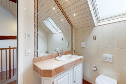 salle de bains avec puits de lumière, inside property, lavabo (ou coiffeuse selon le contexte), vaulted ceiling, et plafond voûté