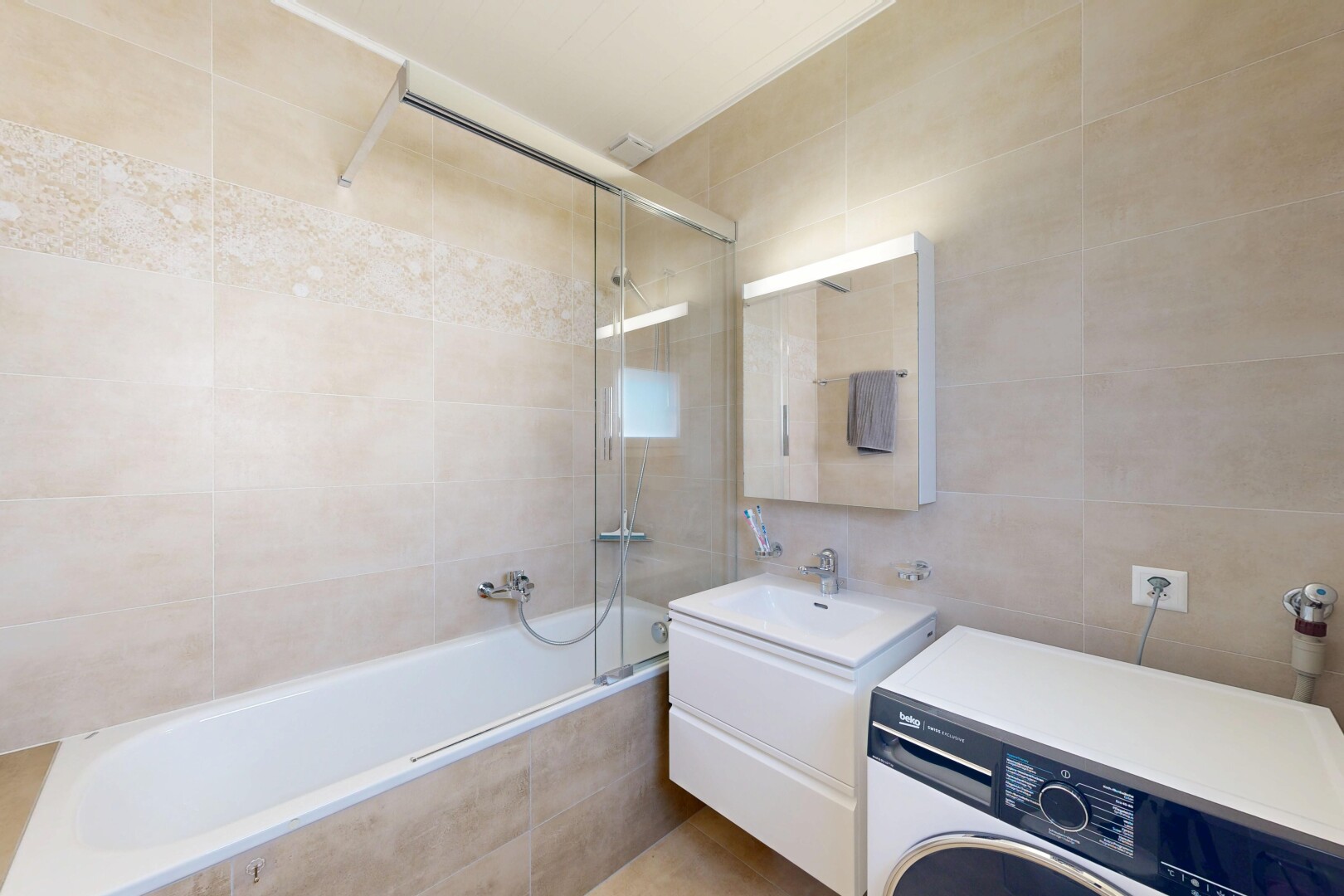 salle de bains avec tile wall, mur en carrelage, lave-linge et sèche-linge, lavabo (ou coiffeuse selon le contexte), et salle de bain complète