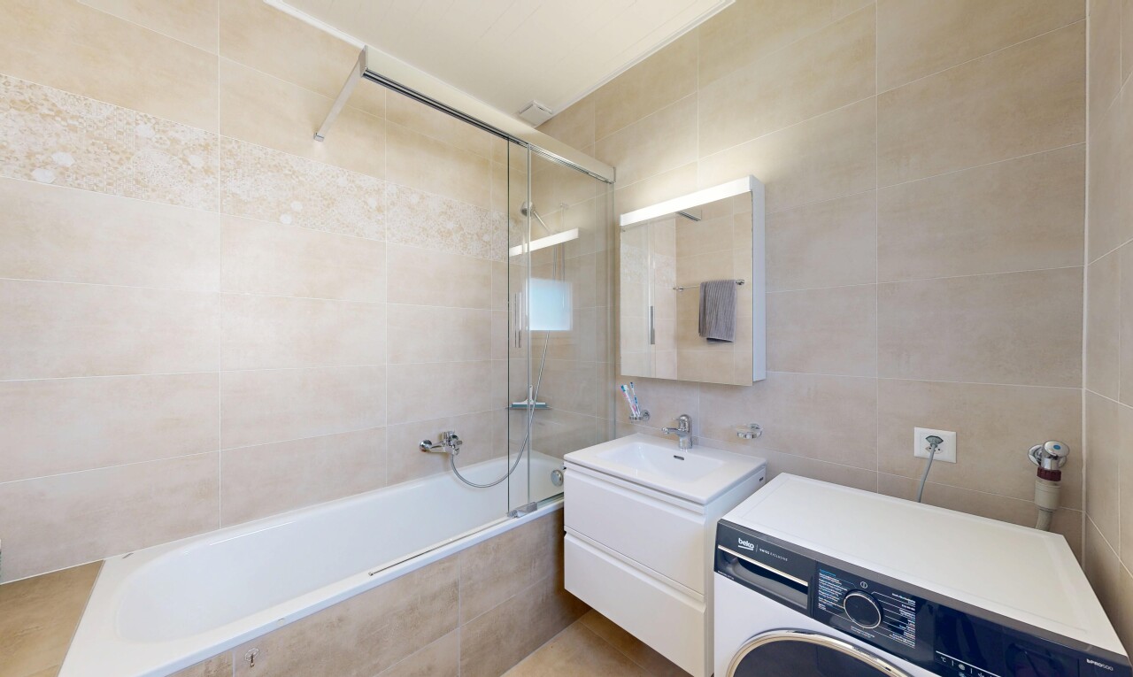 salle de bains avec tile wall, mur en carrelage, lave-linge et sèche-linge, lavabo (ou coiffeuse selon le contexte), et salle de bain complète