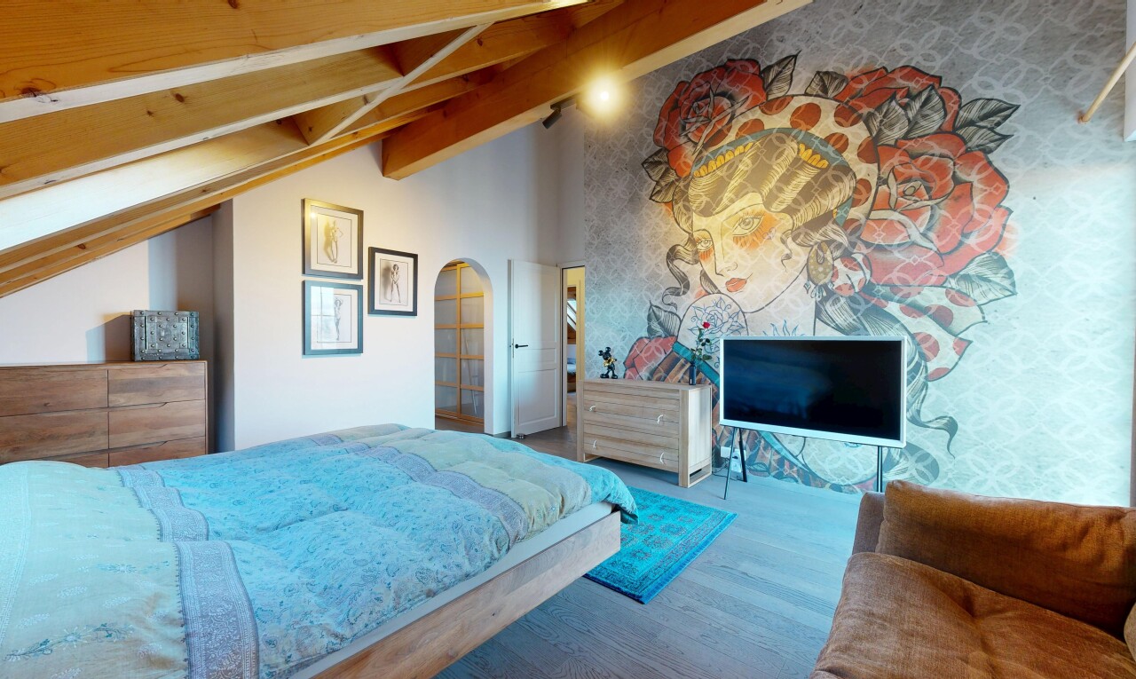 chambre avec télévision, sol en finition bois, wood finish floor, plafond voûté, et vaulted ceiling