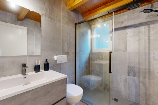 bathroom featuring vanity, a stall shower, tile walls, and beam ceiling
