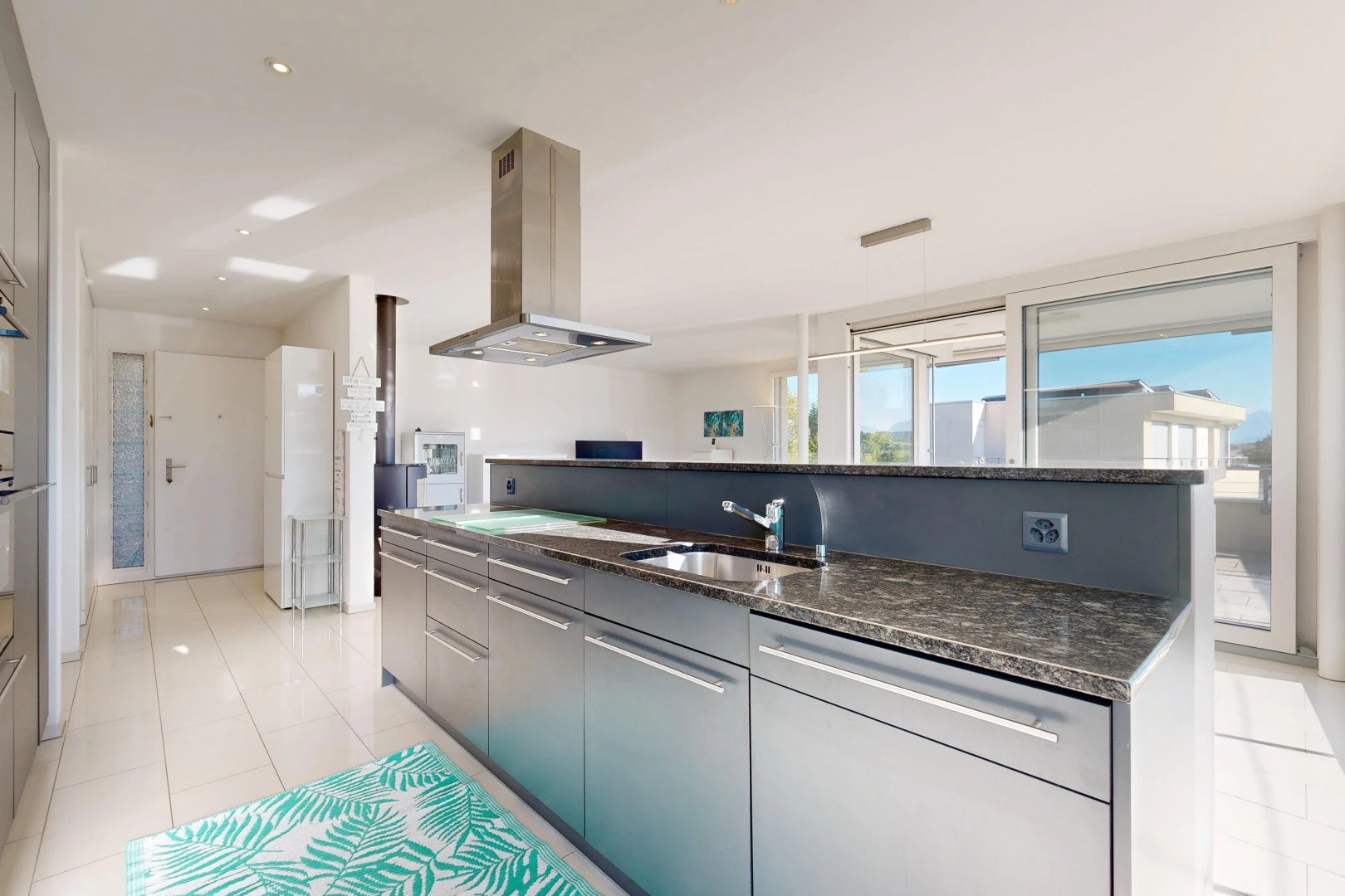 küche mit dunstabzugshaube, two heights countertops, dark countertops, light floor, und stein arbeitsplatten