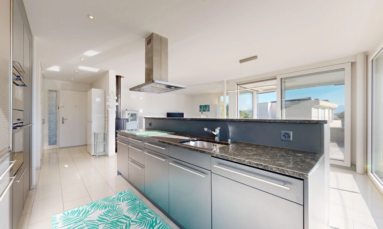 küche mit dunstabzugshaube, two heights countertops, dark countertops, light floor, und stein arbeitsplatten