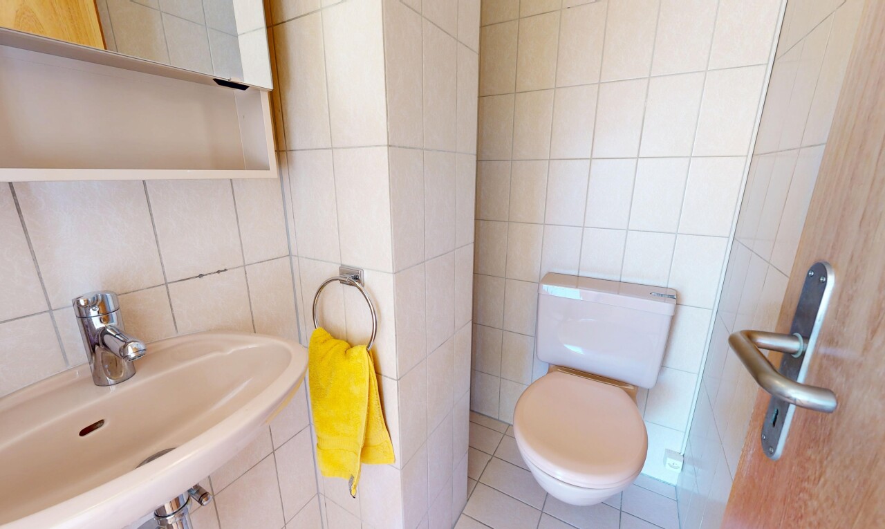 salle de bains avec mur en carrelage, tile wall, toilette, évier, et sol en carrelage