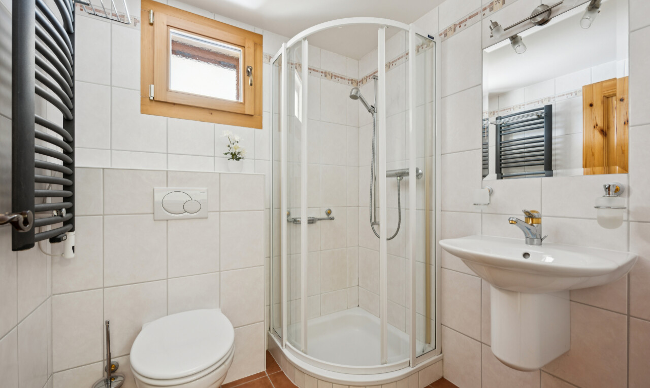 salle de bains avec chauffe-serviettes, salle de bain complète, douche, miroir, et mur en carrelage
