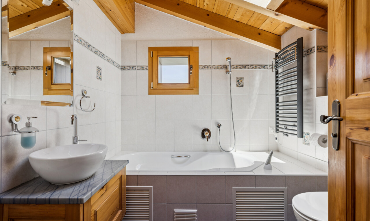 salle de bains avec vaulted ceiling, plafond voûté, tile wall, mur en carrelage, et miroir