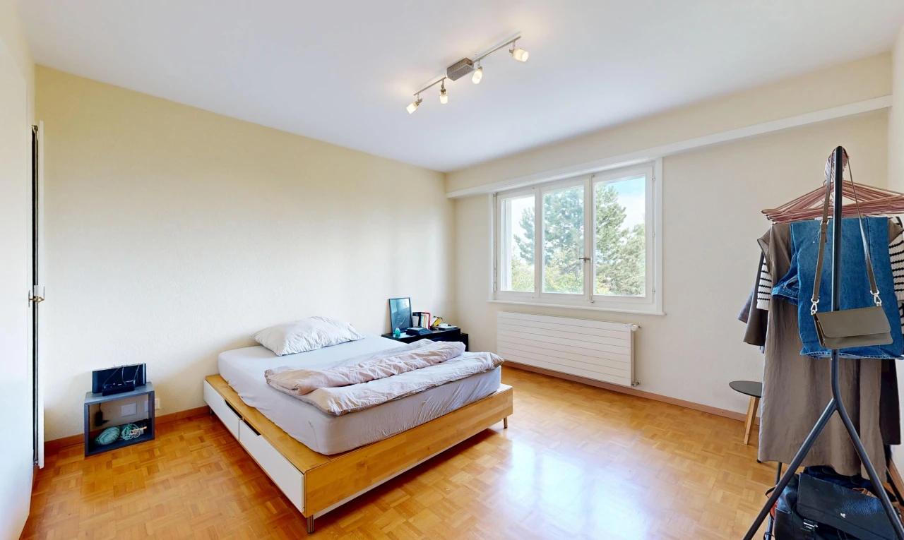 chambre avec éclairage sur rail, radiateur, drywall, cloison sèche, et wood finish floor