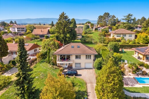 view of home featuring a balcony, a garage, driveway, a tile roof, and a lawn