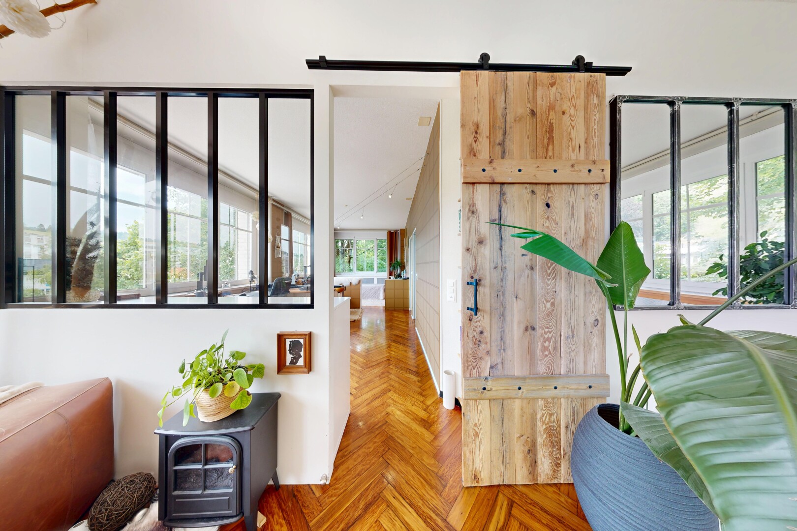 salon avec porte de grange, parquet floor, drywall, cloison sèche, et wood finish floor