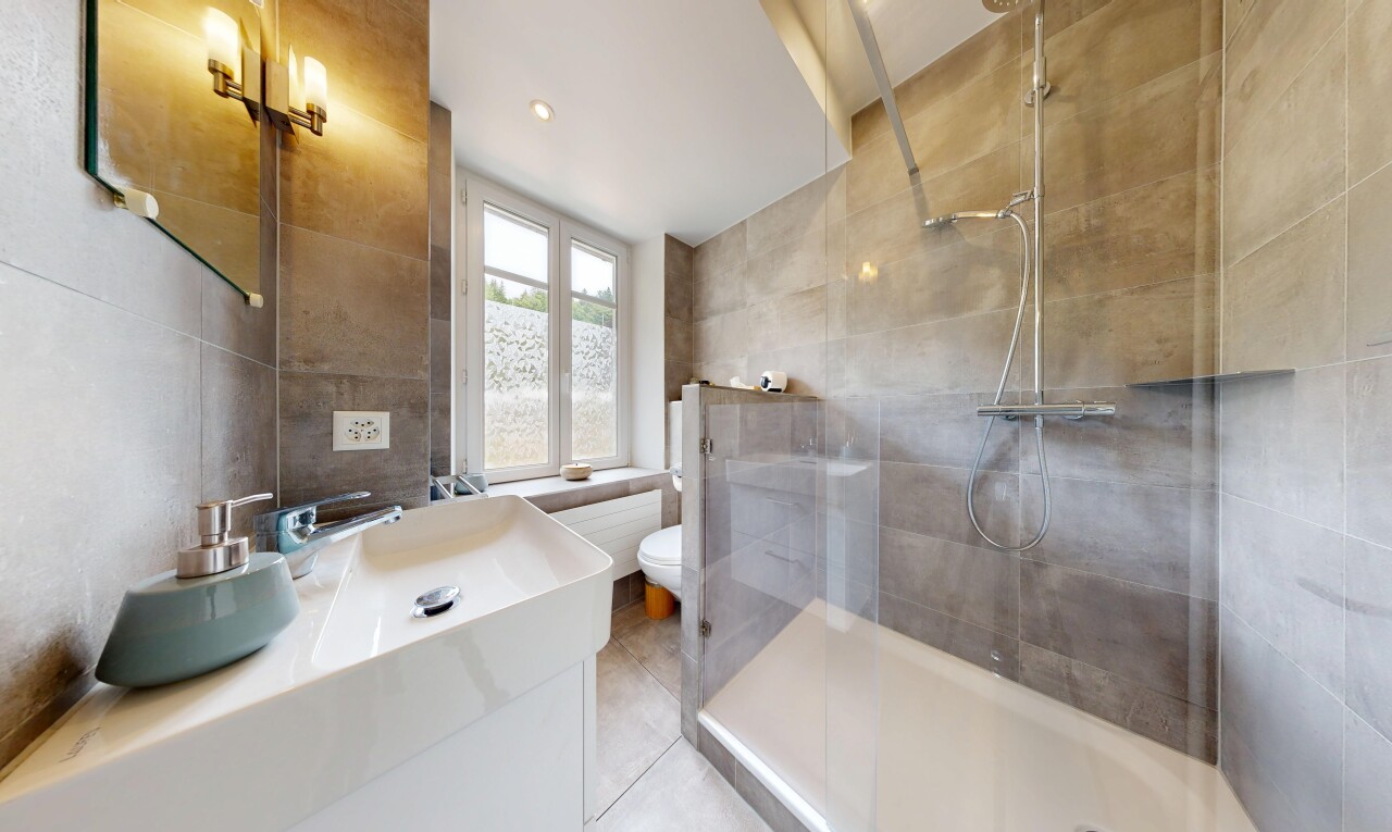 salle de bains avec mur en carrelage, tile wall, miroir, lavabo (ou coiffeuse selon le contexte), et douche