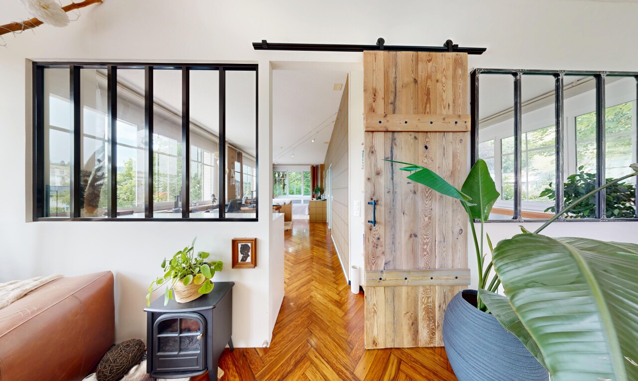 salon avec porte de grange, parquet floor, drywall, cloison sèche, et wood finish floor