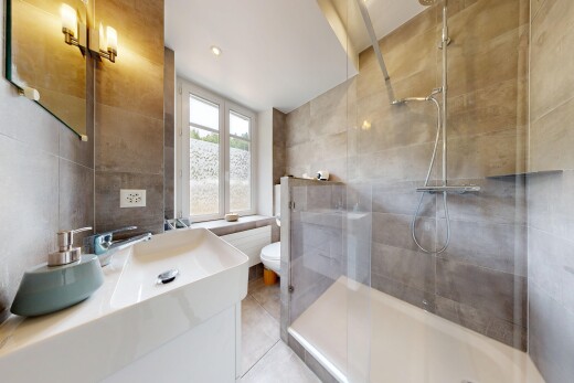 salle de bains avec mur en carrelage, tile wall, miroir, lavabo (ou coiffeuse selon le contexte), et douche
