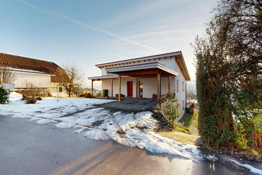 snow covered house featuring a tiled roof, a carport, and stucco siding