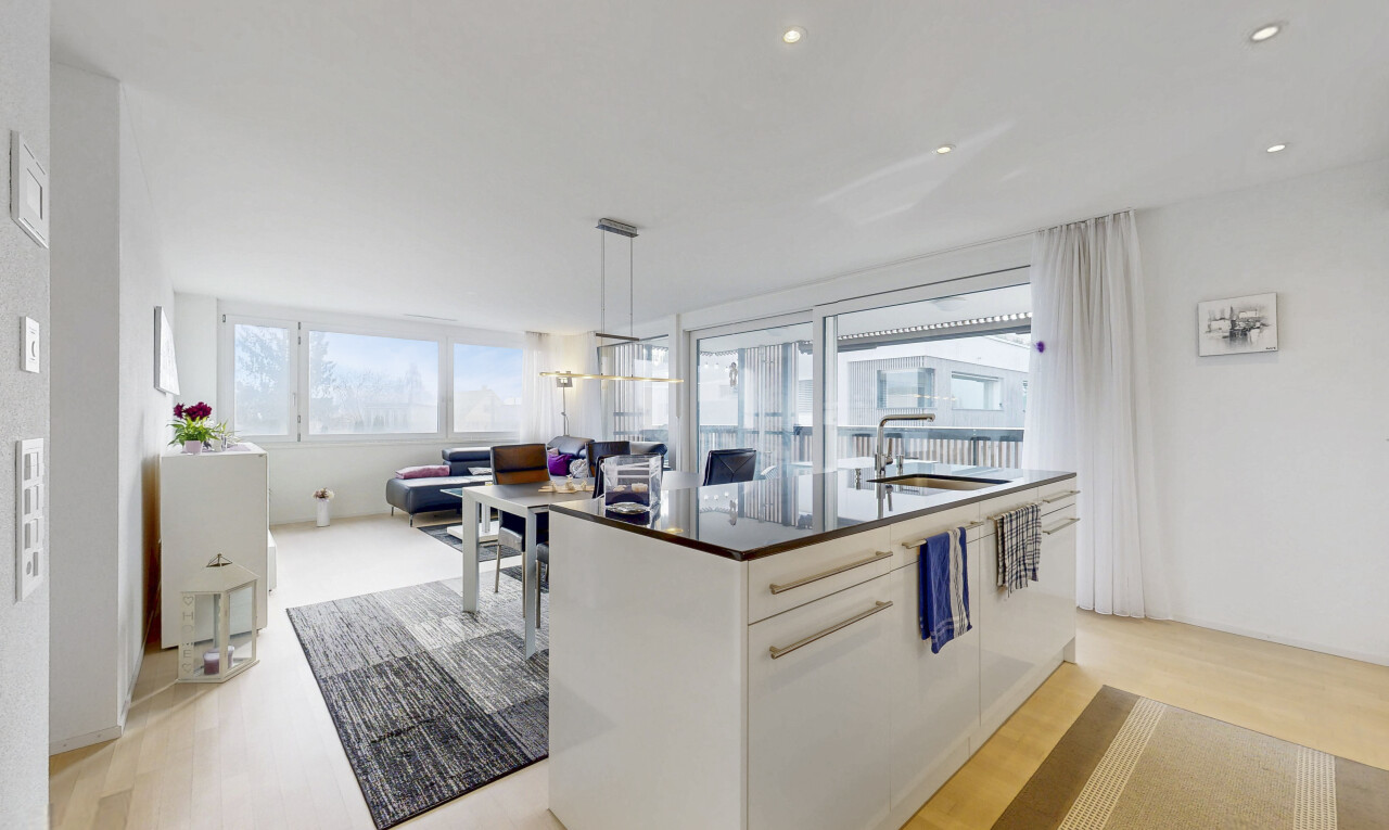 kitchen with an island with sink, light wood-type flooring, pendant lighting, and white cabinets