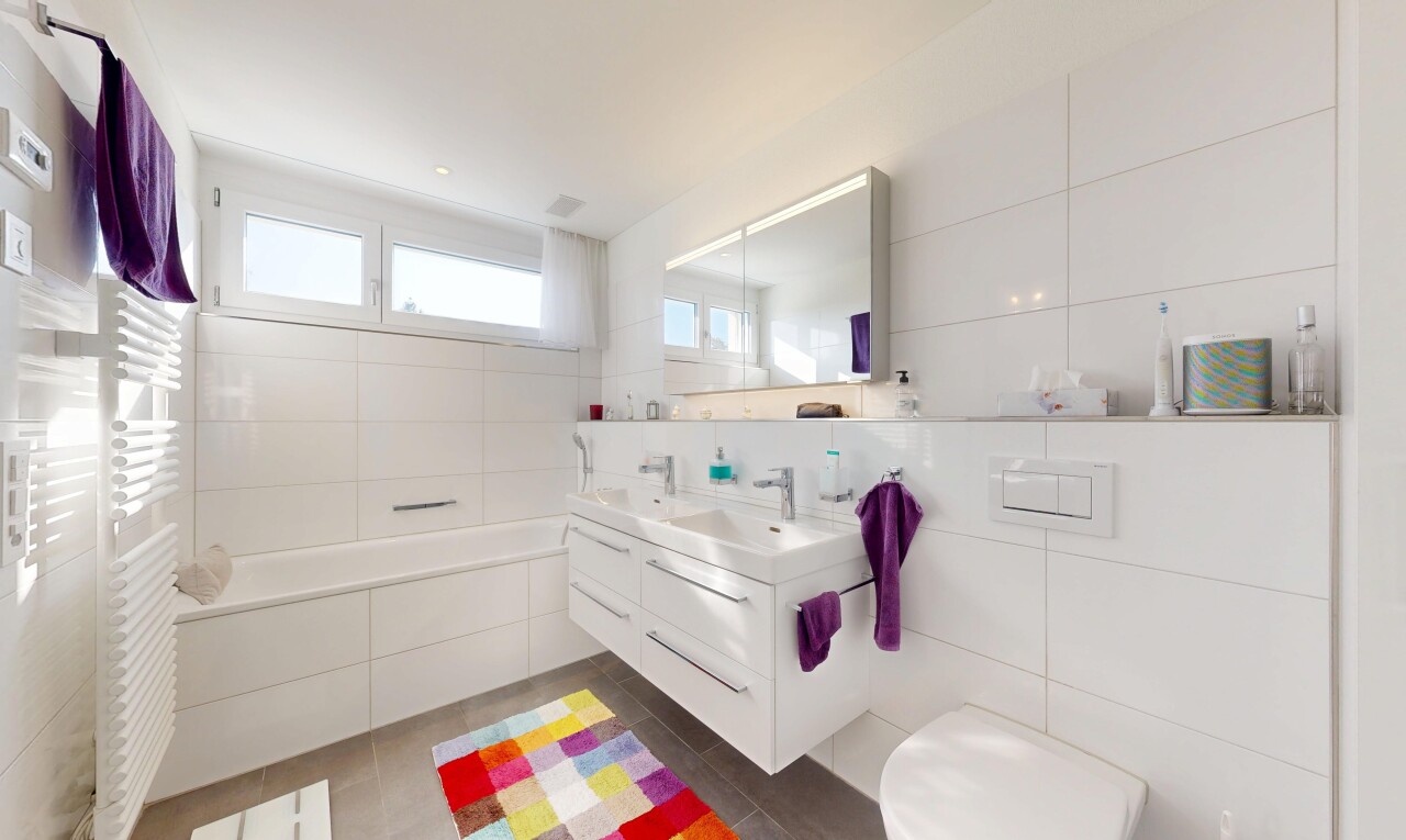 bathroom featuring tile walls, double vanity, a garden tub, radiator, and a towel warming rack