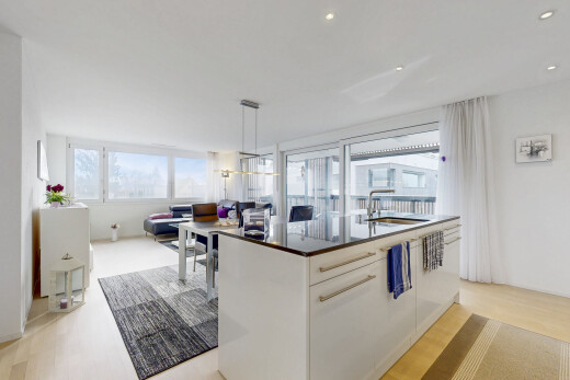 kitchen with an island with sink, light wood-type flooring, pendant lighting, and white cabinets