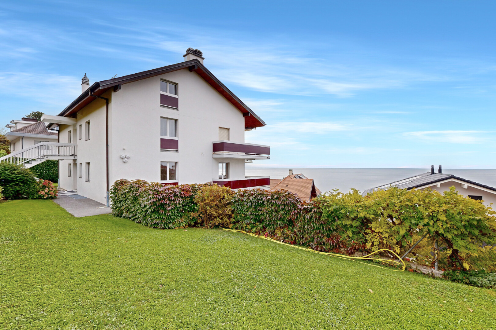 façade avec day time, pelouse, property visible, bardage en stuc, et ocean view