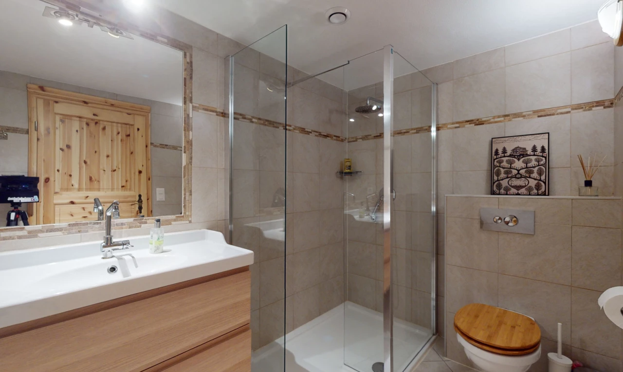 salle de bain avec mur carrelé, carrelage, miroir, meuble-lavabo, et douche