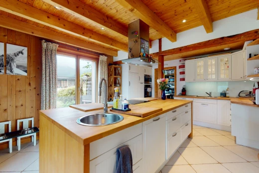 cuisine avec îlot de cuisine, poutres apparentes, meubles vitrés, et plan de travail en bois