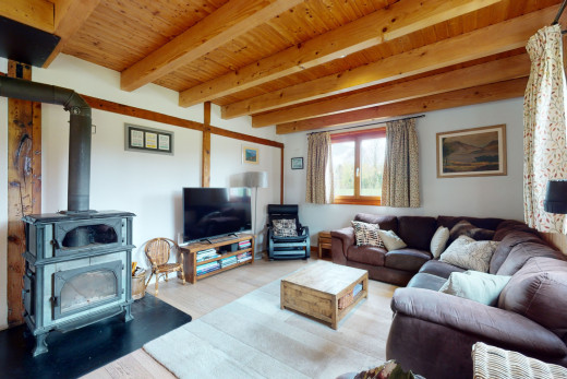 wohnzimmer mit fernsehen, balkendecke, holzofen, holzdecke, und natürliches licht