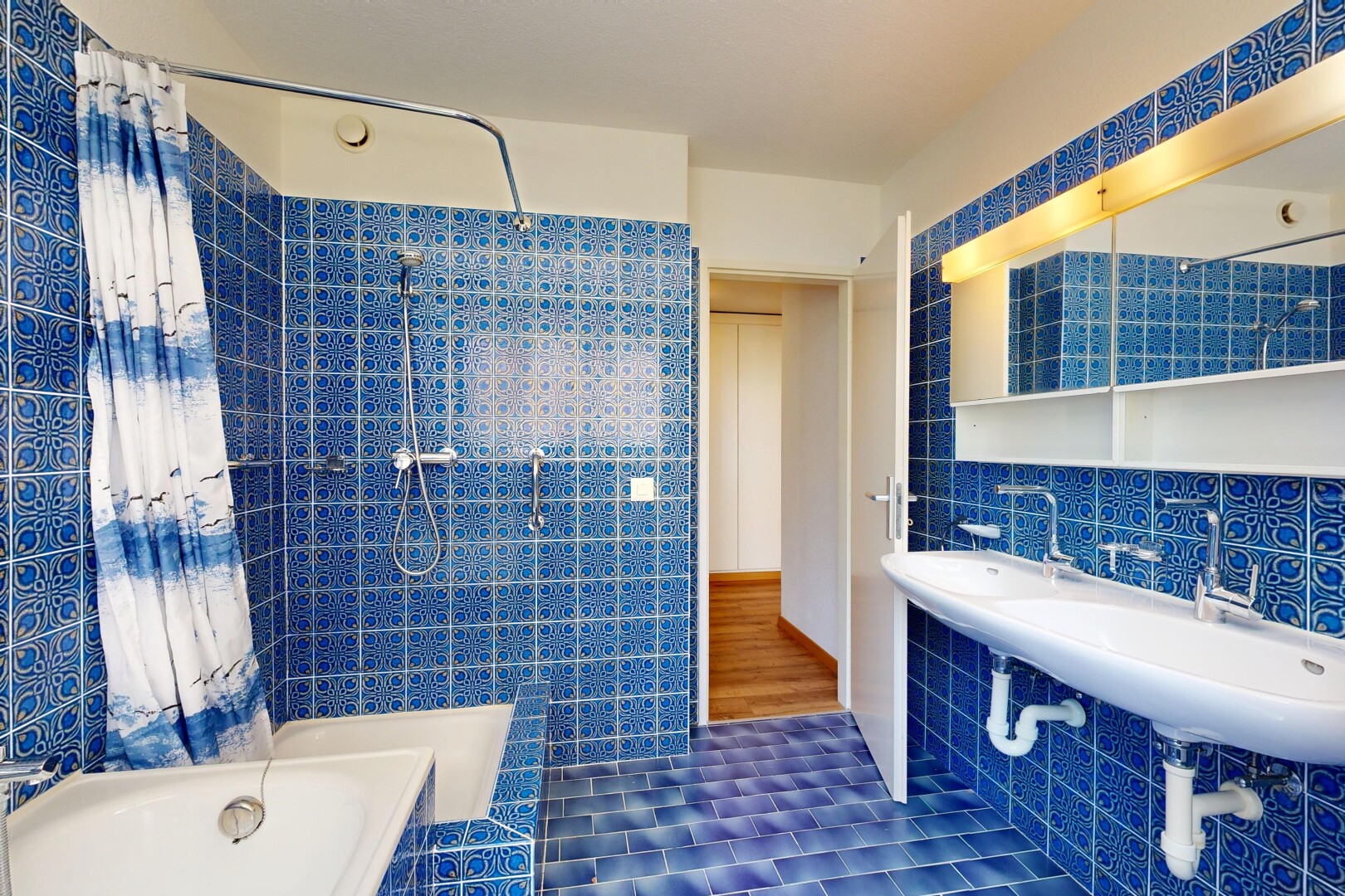 full bath featuring tile walls, tiled shower / bath, and dark tile patterned floors