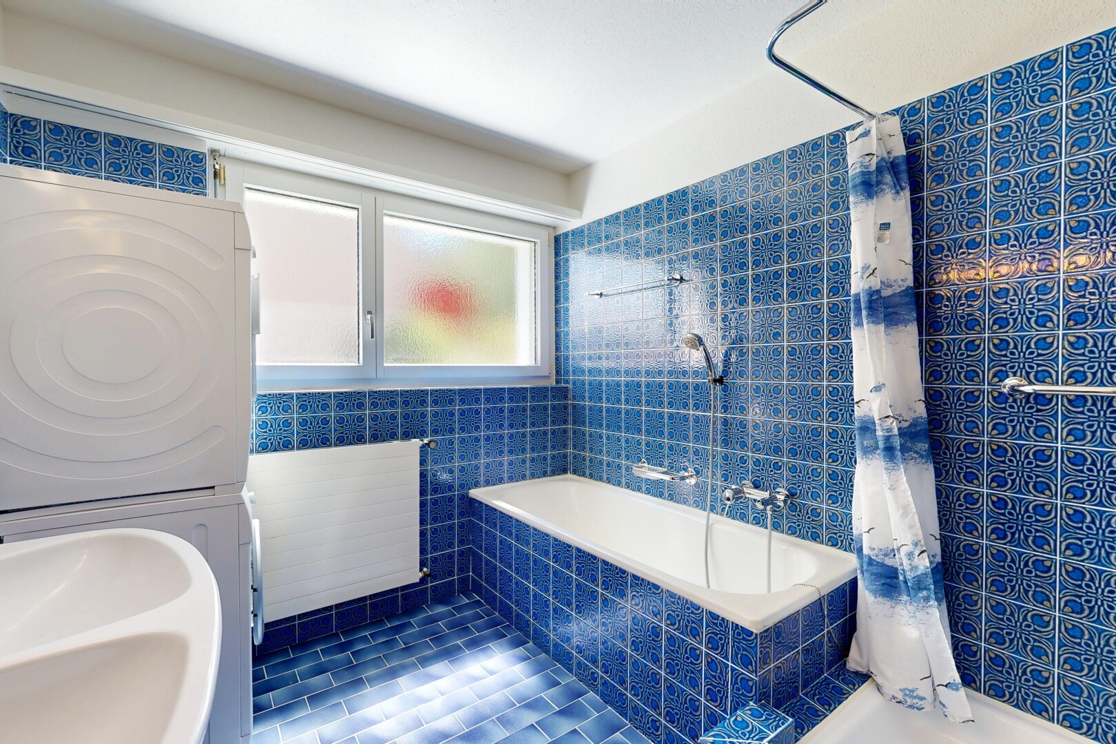 bathroom with tiled shower / bath combo, stacked washing machine and dryer, and tile walls