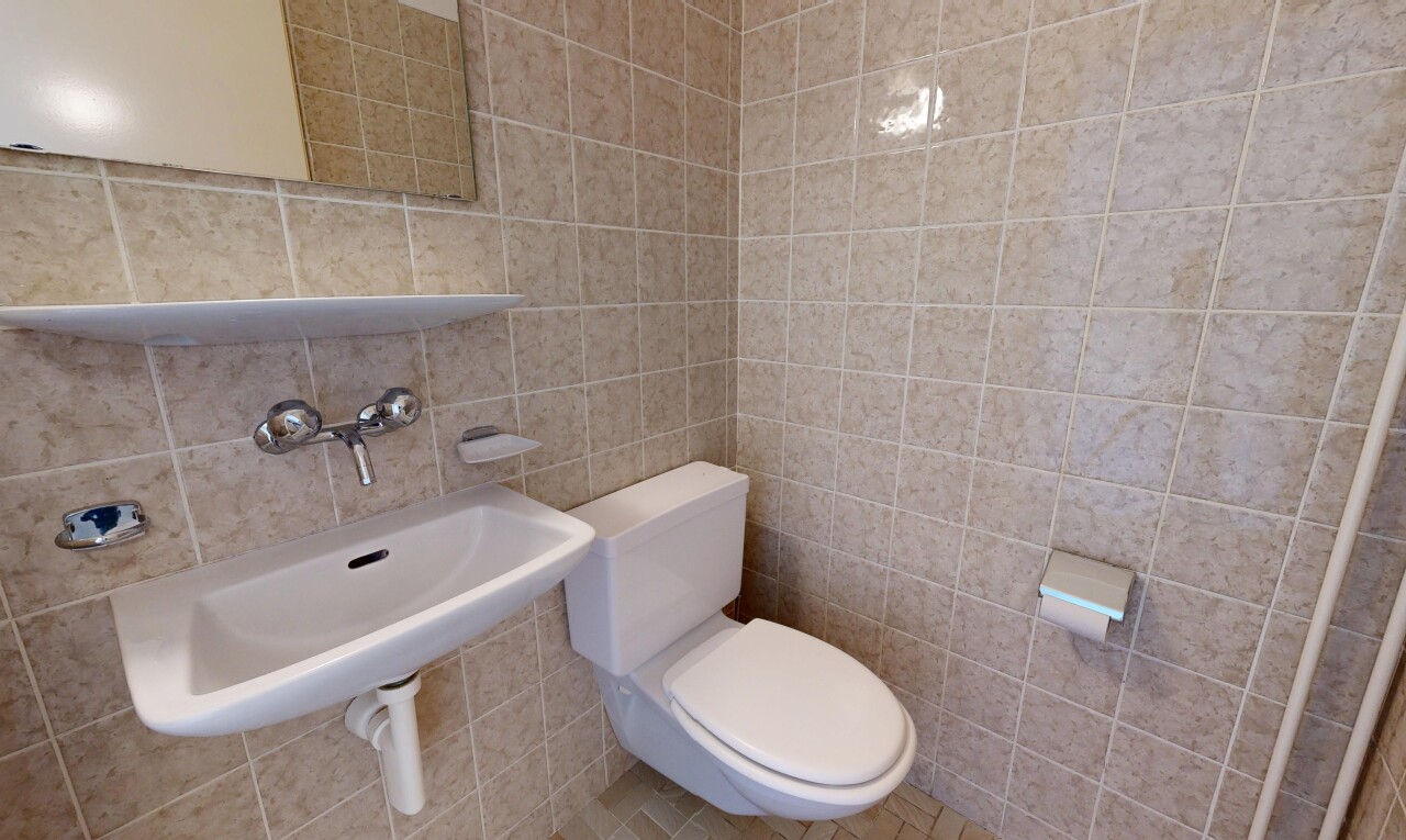 half bathroom with toilet and tile walls