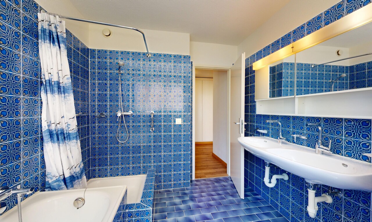 full bath featuring tile walls, tiled shower / bath, and dark tile patterned floors