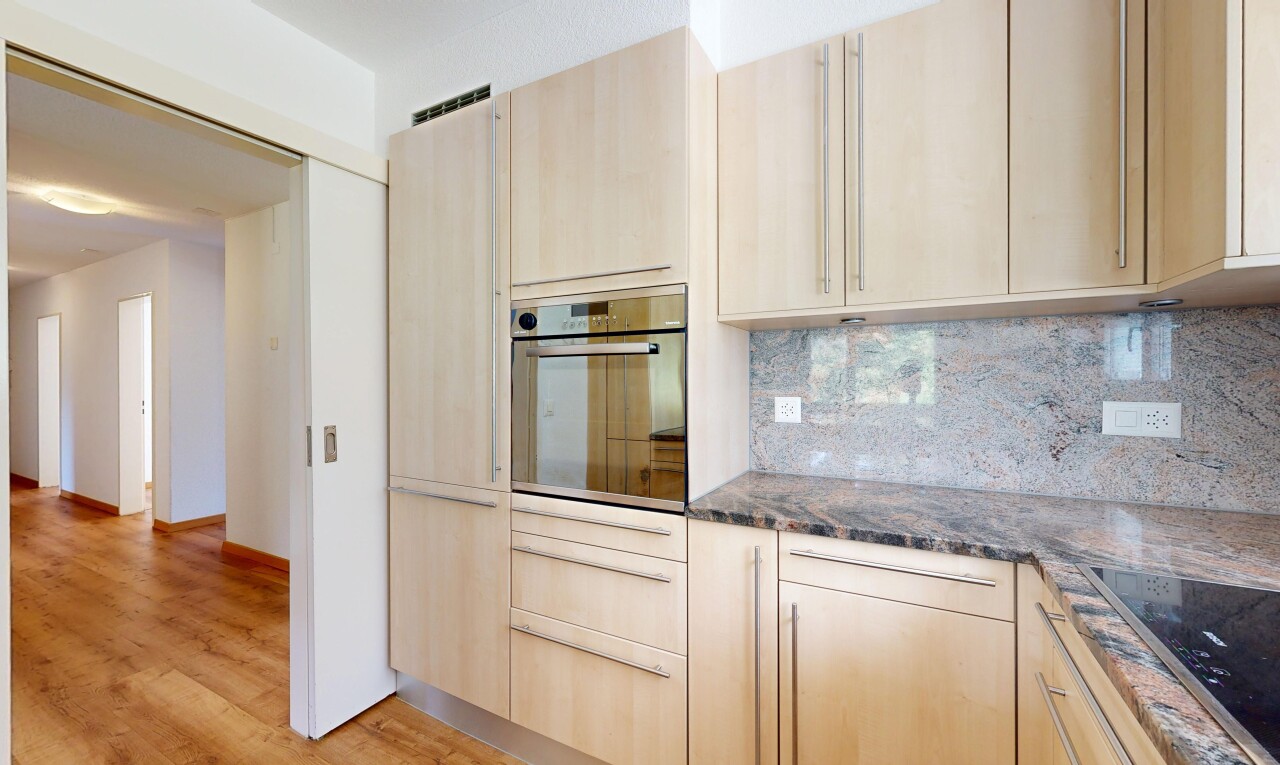 kitchen featuring dark stone counters, oven, light wood finish cabinets, and tasteful backsplash