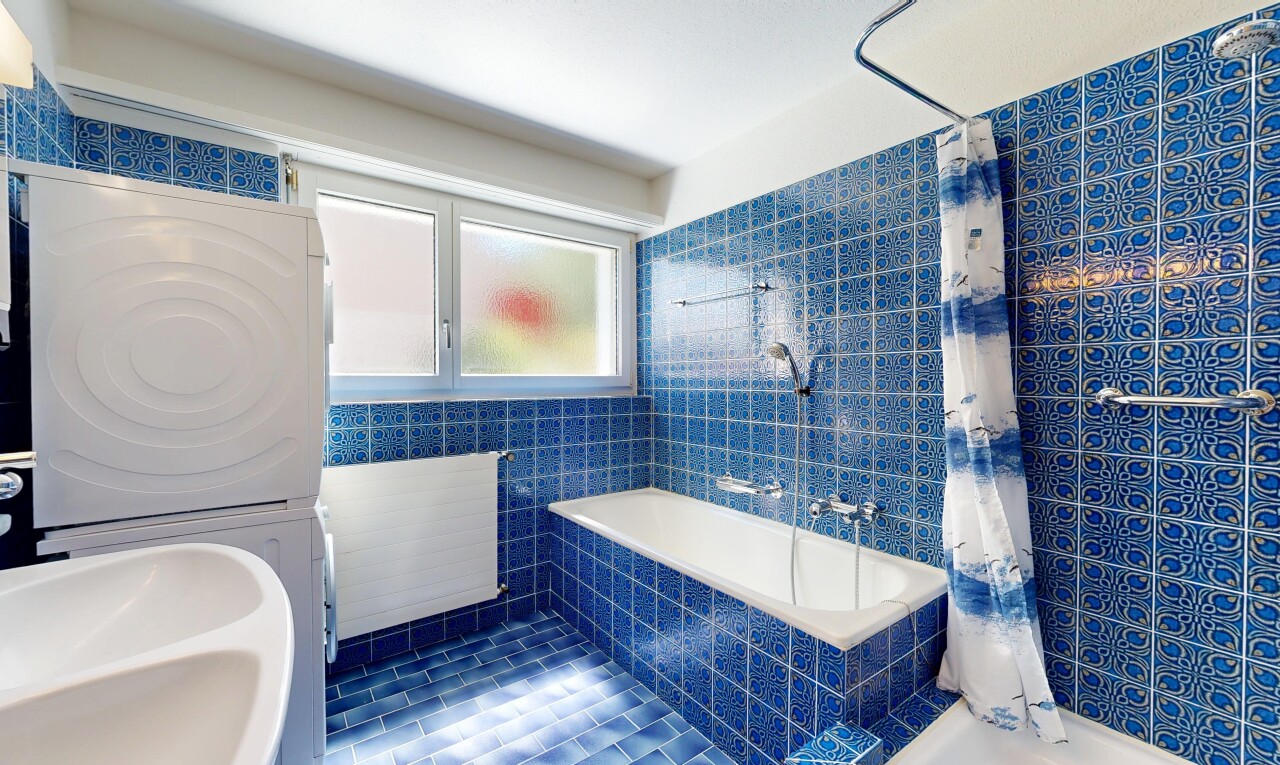 bathroom with tiled shower / bath combo, stacked washing machine and dryer, and tile walls
