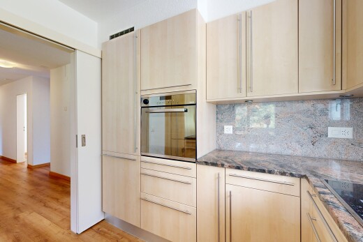 kitchen featuring dark stone counters, oven, light wood finish cabinets, and tasteful backsplash