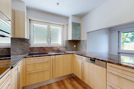 kitchen with light wood finish cabinetry, light wood finished floors, stainless steel appliances, backsplash, and dark stone counters