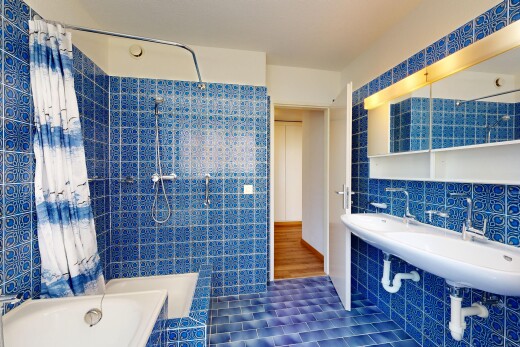 full bath featuring tile walls, tiled shower / bath, and dark tile patterned floors
