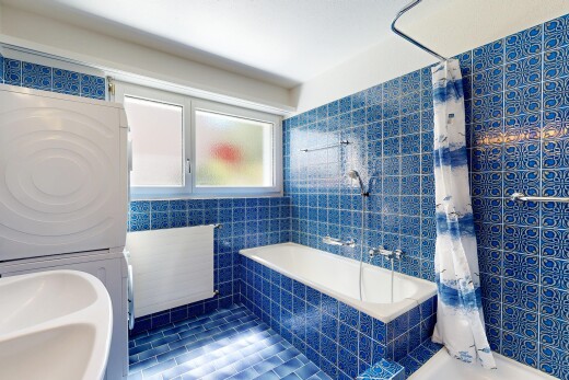 bathroom with tiled shower / bath combo, stacked washing machine and dryer, and tile walls