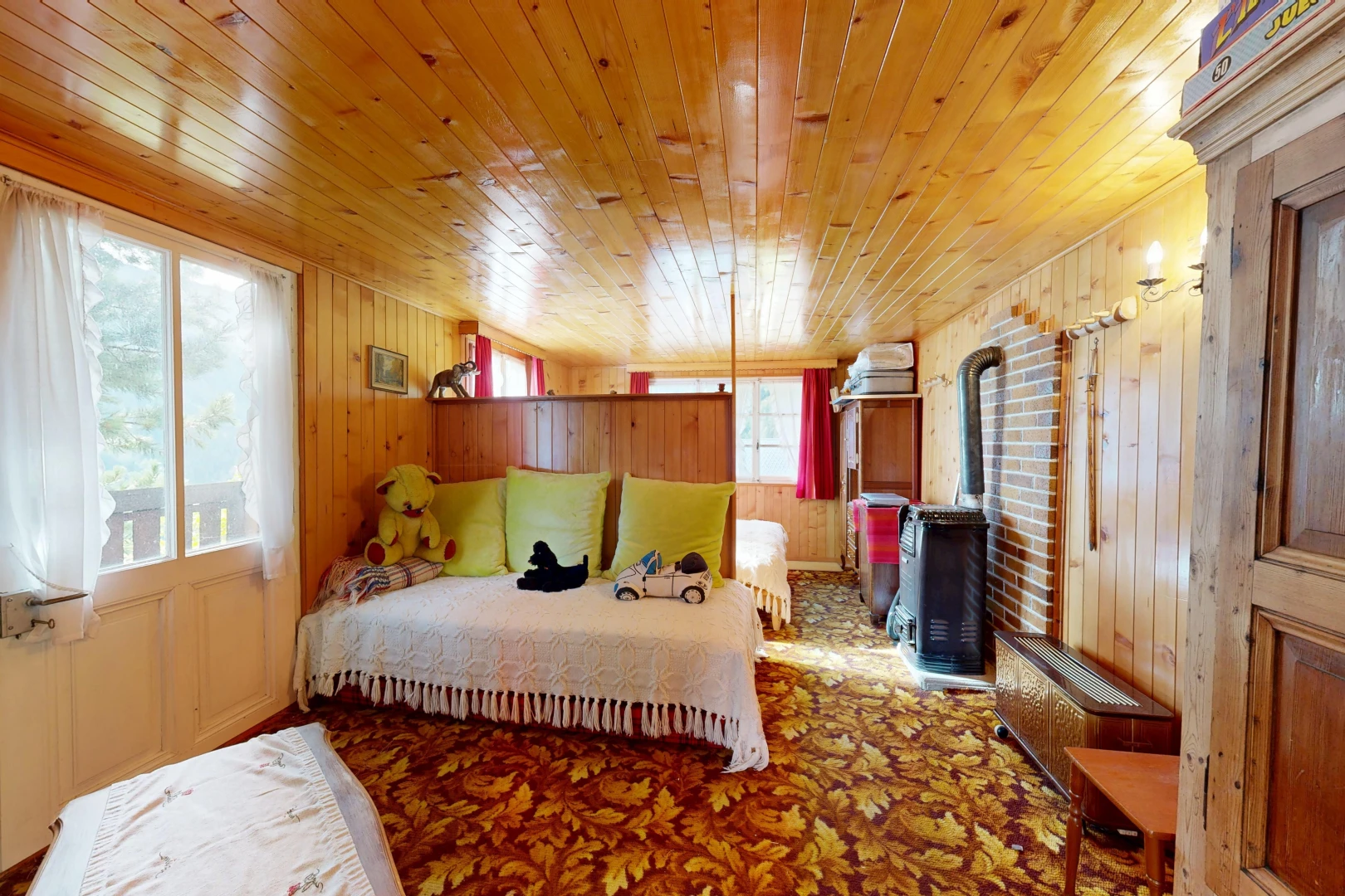 chambre avec poêle à bois, dated wood wall, carpet, moquette, et wood wall